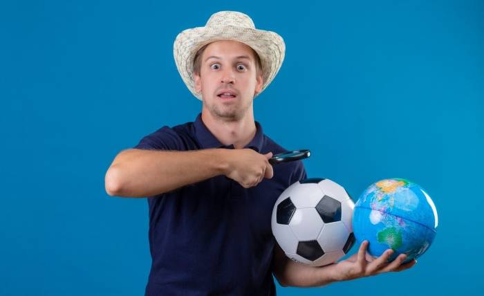 Is UFAGAME an Excellent Choice for Novice Football Bettors? young handsome man summer hat holding soccer ball globe going look globe through magnifying glass looking surprised amazed standing blue background 141793 23664